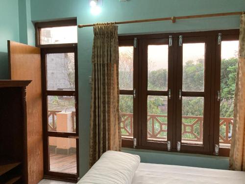 索拉哈Sauraha Guest House的一间带床和大窗户的卧室