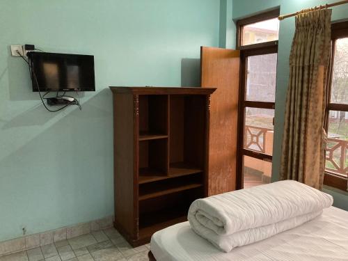 1 dormitorio con TV, 1 cama y 1 tvictericter en Sauraha Guest House en Sauraha