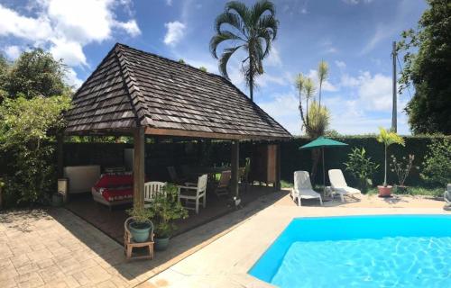 a house with a gazebo and a swimming pool at Chalet Ohana, airport family house in Faaa