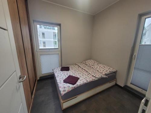 een kleine slaapkamer met een bed en 2 ramen bij Apartament Longinówka in Brodnica
