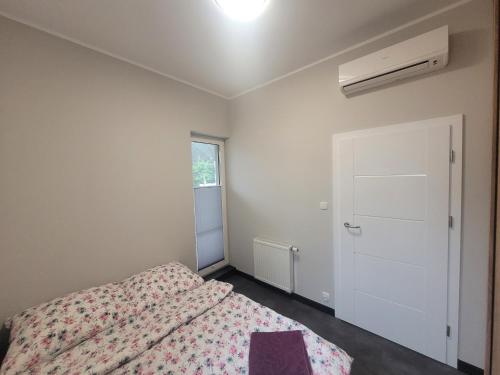 Schlafzimmer mit einem Bett, einem Fenster und einer Tür in der Unterkunft Apartament Longinówka in Brodnica