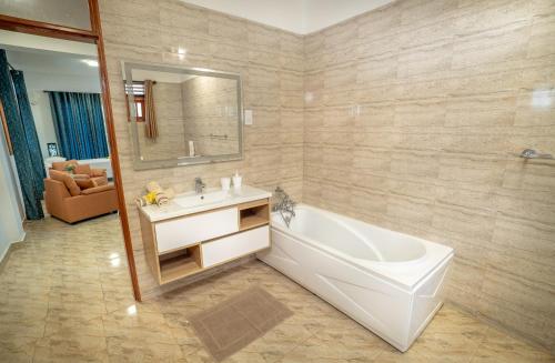 bagno con vasca, lavandino e specchio di La Belle Residence Self Catering Accommodation a Beau Vallon
