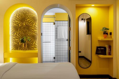 a bedroom with a bed and a shower with a mirror at Myhotel Cmyk@Ratchada in Bangkok