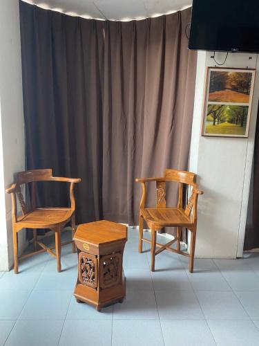 two chairs and a table in front of a curtain at Sun Tree Hotel in Kampong Kerayong