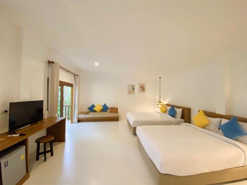 a hotel room with two beds and a television at Issara Beach Resort Beachfront in Sichon