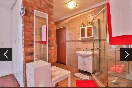 a bathroom with a glass shower and a sink at The Link on Bonsai in Kempton Park