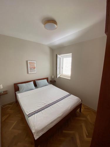 a bedroom with a white bed with a window at First line Apartment Petrovac in Petrovac na Moru
