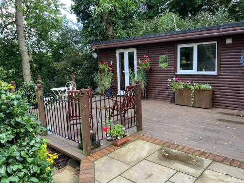 Cabaña pequeña con terraza con mesa y sillas en Eve’s Contemporary Cabin in Kent Woodland Setting, en Kent