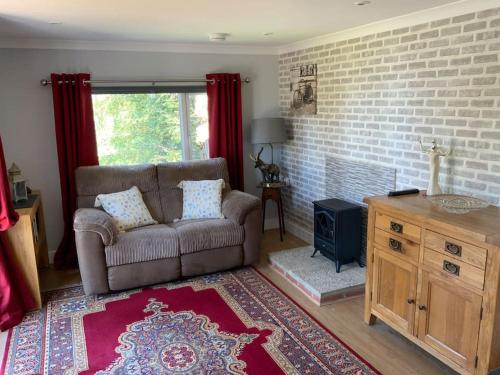 sala de estar con sofá y chimenea en Eve’s Contemporary Cabin in Kent Woodland Setting, en Kent