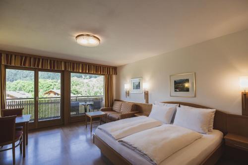 a hotel room with a bed and a balcony at Hotel Brötz in Rasùn di Sotto