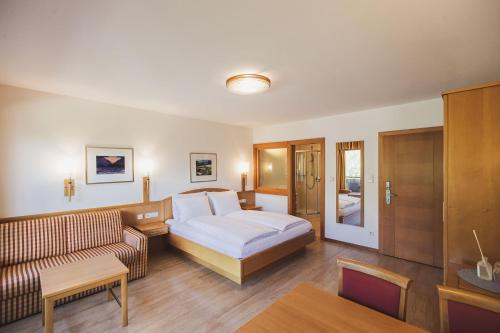 a hotel room with a bed and a couch at Hotel Brötz in Rasùn di Sotto
