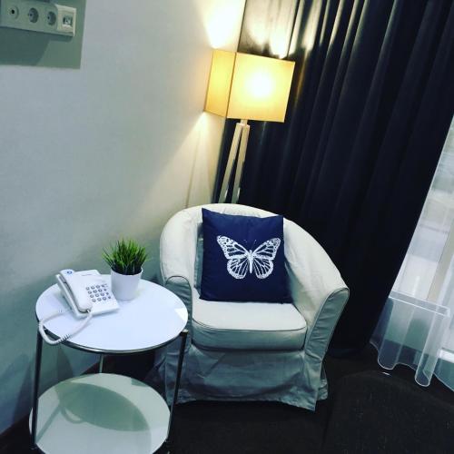 a chair with a butterfly pillow on it next to a table at Orynbor Boutique Hotel in Astana