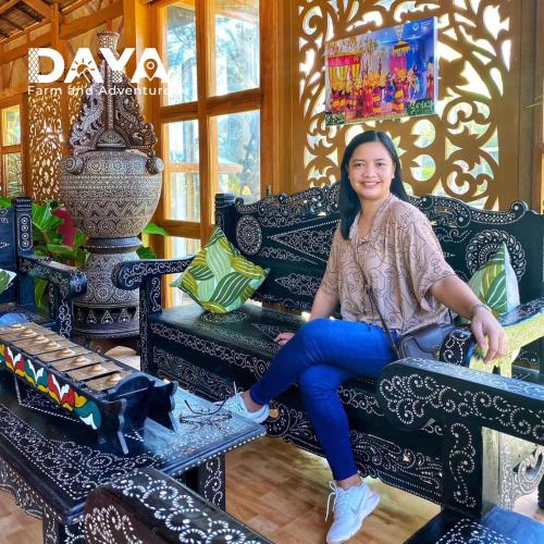 a woman sitting on a bench in a room at Daya Farm and Adventure in Banay-Banay