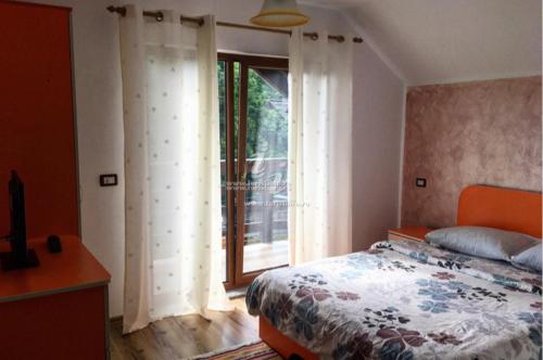 ein Schlafzimmer mit einem Bett und einem großen Fenster in der Unterkunft Casa de vacanța Ariana in Borşa