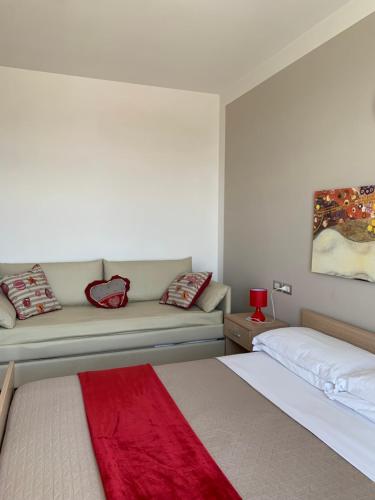a white bedroom with a bed and a couch at Residence Alba in Riccione