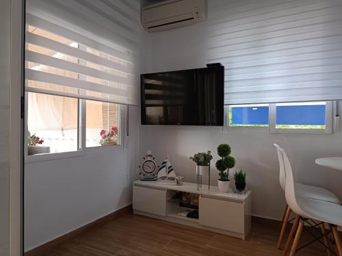 a living room with a table and a tv on the wall at Apartamento Caravaca in Santa Pola