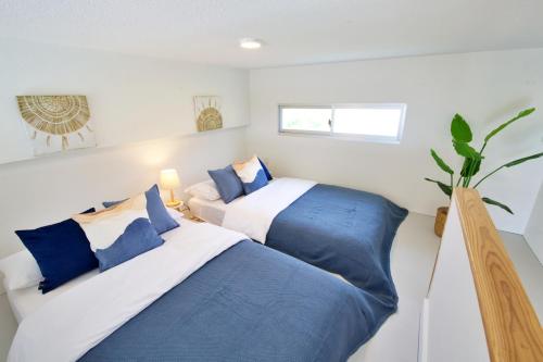 a bedroom with two beds with blue pillows at サンセットビューコテージ本部 in Motobu