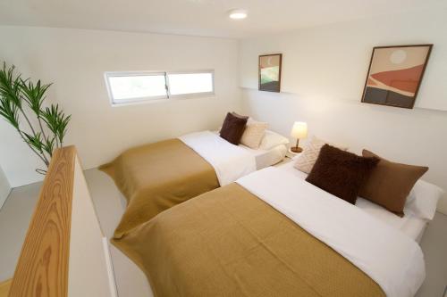 two beds in a room with white walls at サンセットビューコテージ本部 in Motobu