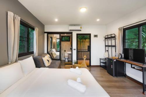 a bedroom with a large white bed and a living room at Naramountainkhaoyai 04 in Ban Tha Chang