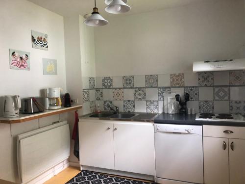 a small kitchen with white cabinets and a sink at Grand appartement en RDC Vallée de Campan in Campan