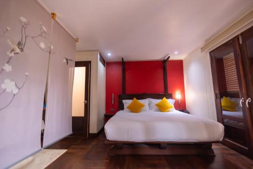 a bedroom with a large white bed with yellow pillows at Ancient Luangprabang Hotel in Luang Prabang