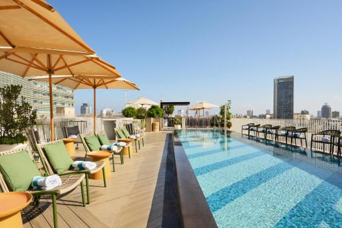 a swimming pool with chairs and umbrellas on a building at Alberto by Isrotel Design in Tel Aviv