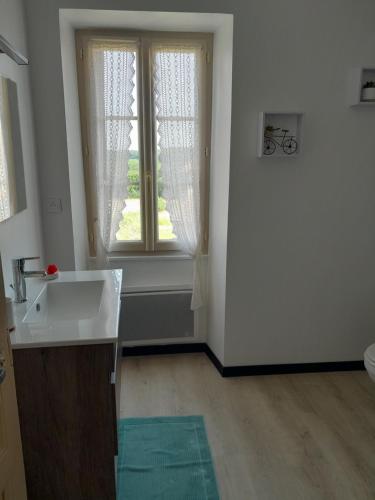 une salle de bain blanche avec un lavabo et une fenêtre dans l'établissement maison de campagne en pierre, à Dégagnac