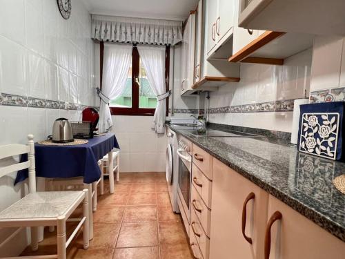 a kitchen with white cabinets and a blue counter top at Casa adosada en Argoños in Argoños