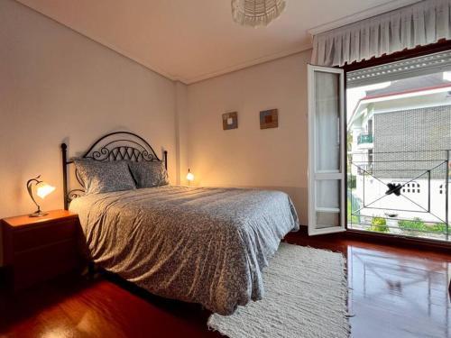 sypialnia z łóżkiem i dużym oknem w obiekcie Casa adosada en Argoños w mieście Argoños