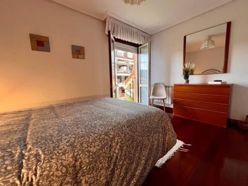 a bedroom with a bed and a dresser and a window at Casa adosada en Argoños in Argoños