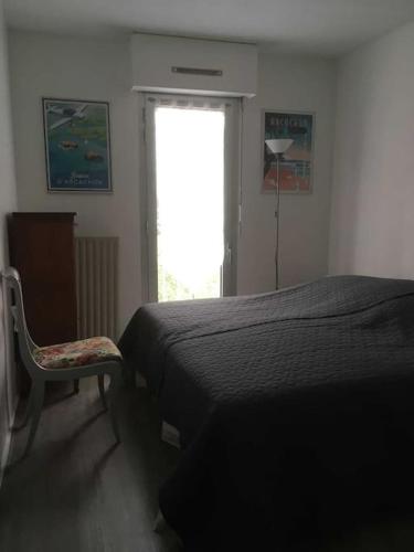 une chambre avec un lit, une chaise et une fenêtre dans l'établissement T2 de 50 m2 + balcon + parking pour 4 personnes, à Arcachon