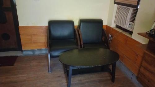 deux chaises et une table dans une pièce dans l'établissement Corbett Call Resort, à Rāmnagar