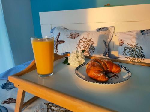 un tavolo con un bicchiere di succo d'arancia e un cornetto di Summer Smile by Euxin Accomodations a Năvodari