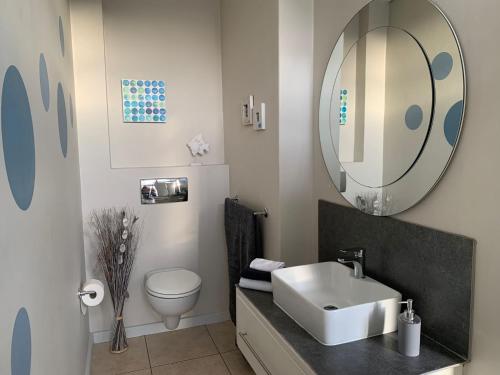 bagno con lavandino, servizi igienici e specchio di City Penthouse Kapstadt a Città del Capo