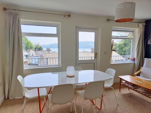 une salle à manger avec une table blanche, des chaises et des fenêtres dans l'établissement Crow's Nest Glandore - 3 - Self Catering, à Glandore