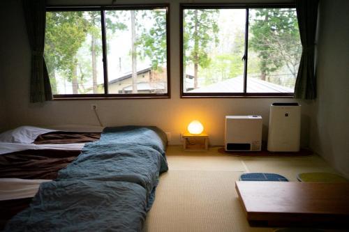 a bedroom with two beds and two windows at LAMP Nojiriko in Shinano