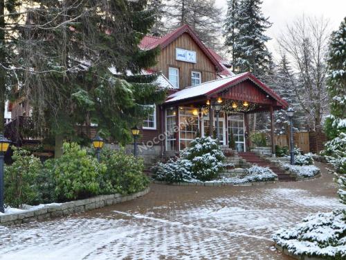 Un bâtiment avec une horloge en haut dans la neige dans l'établissement Oro Cavallo, à Karpacz