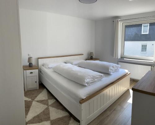 a white bed in a bedroom with a window at Ferienwohnung Hildfeld KORS in Winterberg