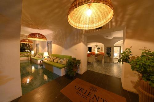 a living room with a green couch and chandeliers at Hotel Terme Oriente - Beach & SPA in Ischia