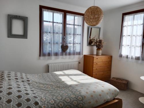 - une chambre avec un lit, une commode et des fenêtres dans l'établissement Location maison à l'Epine sur Île de Noirmoutier, à LʼÉpine