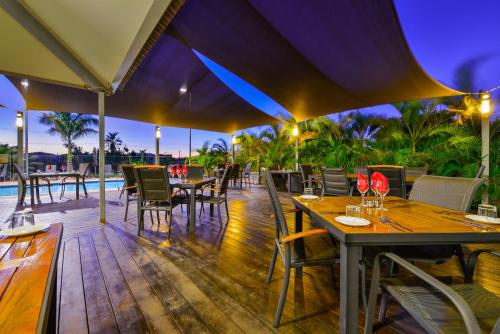 a restaurant with tables and chairs on a deck at Exmouth Escape Resort in Exmouth