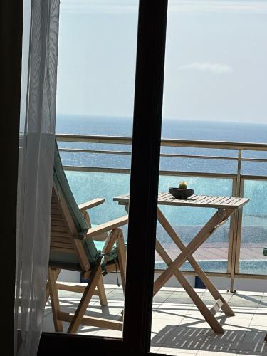 a table and a chair on a balcony with the ocean at Ericeira Sea&Sun Apartment 3 in Ericeira