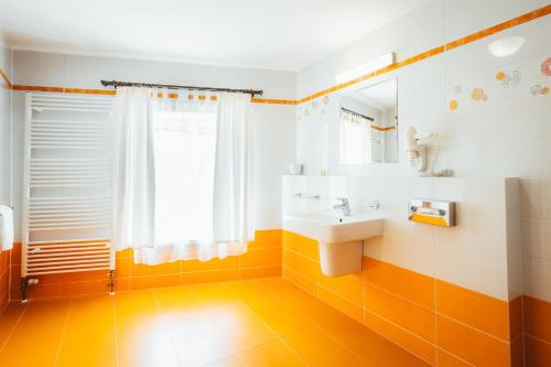 an orange and white bathroom with a sink and a mirror at Sv. Hubertus in Český Krumlov