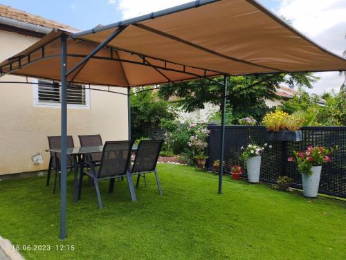 a patio umbrella with chairs and a table in a yard at Limor-resident in Qasrîne