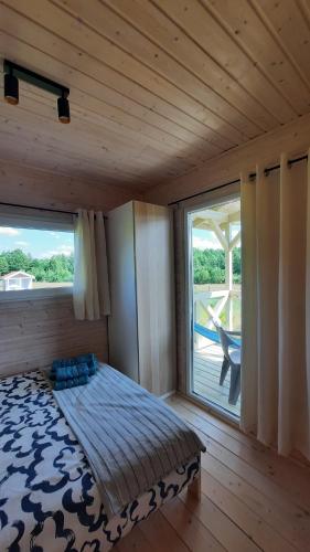 a bedroom with a bed and a large window at Domki Wysokie Trawy Zdory in Pisz