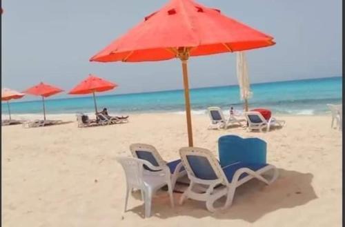 a group of chairs and an umbrella on the beach at Aqua view North coast-الكيلو 91- in El Alamein
