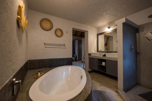 a large white tub in a bathroom with a sink at Lindiwe Safari Lodge in Hoedspruit
