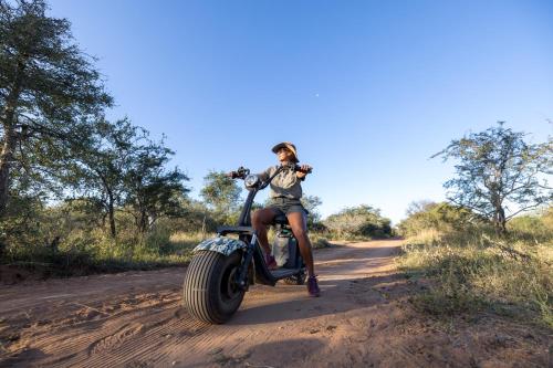a woman sitting on a motorcycle on a dirt road at Lindiwe Safari Lodge in Hoedspruit