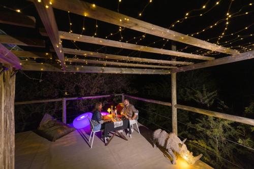 two people sitting at a table on a patio at night at Lindiwe Safari Lodge in Hoedspruit