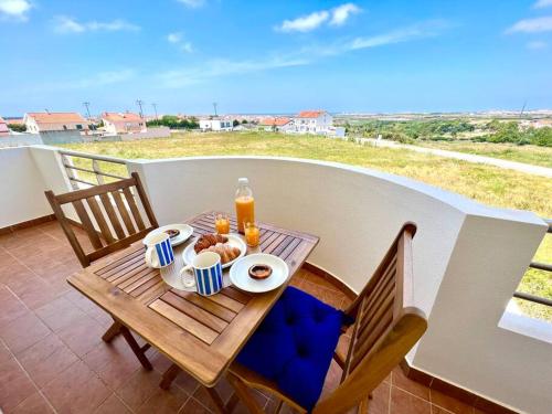 a table with food and drinks on a balcony at Apartamento T2 com vista panorâmica sobre a costa in Atouguia da Baleia